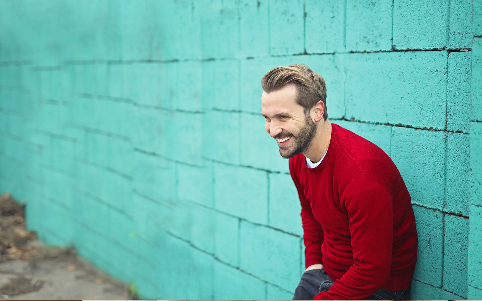 Man in red sweater leaning against the wall
