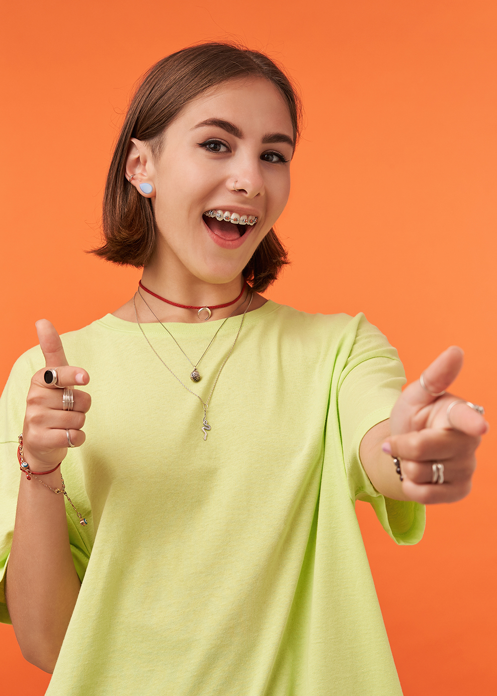 Girl wearing traditional braces doing finger guns at the camera