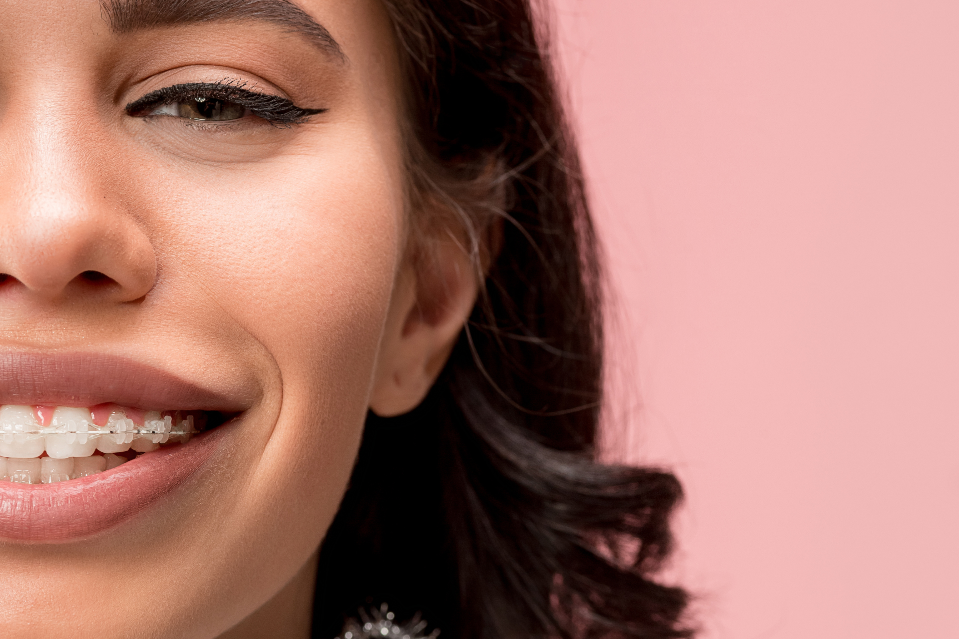 girl with clear braces on pink background