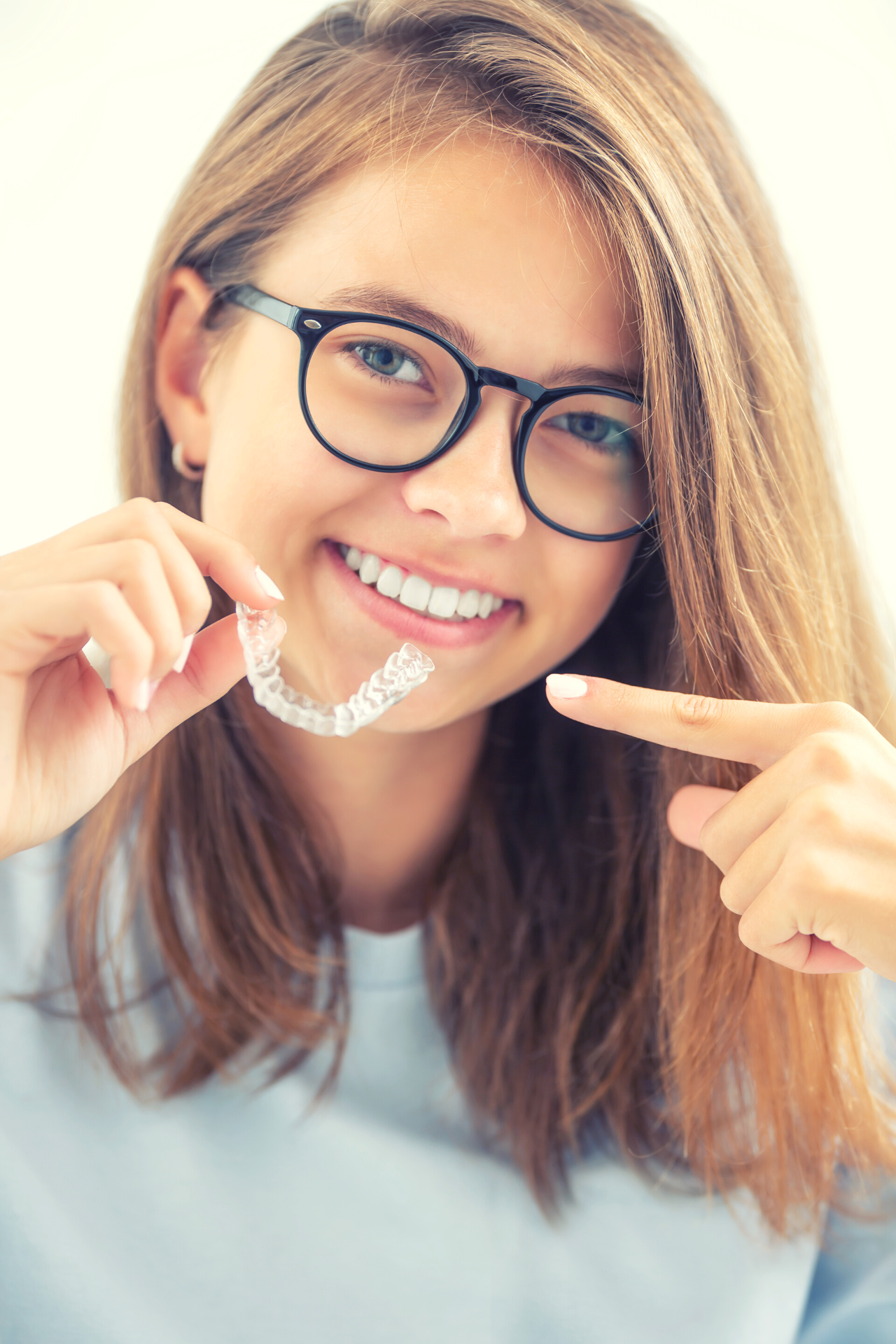 girl holding clear retainer and smiling