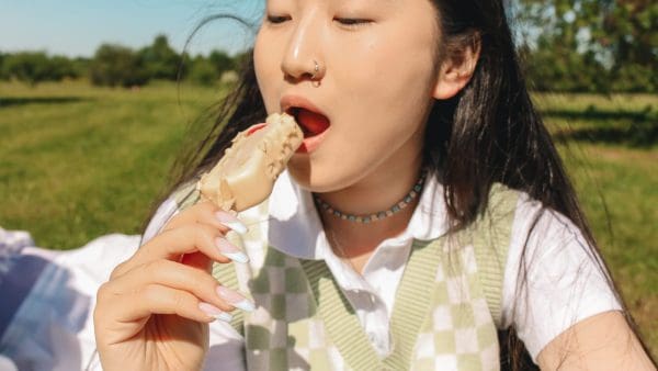 Girl eating an ice cream bar outdoors, a soft treat that is easy when eating with braces