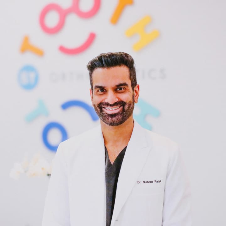 tooth-by-tooth-orthodontics-tooth-by-tooth-dr-patel-dr-nishant-patel-white-coat-smiling-portrait