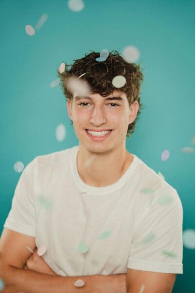 tooth-by-tooth-orthodontics-tooth-by-tooth-dr-patel-home-slider-boy-patient-with-big-smaile-folding-arms-confetti