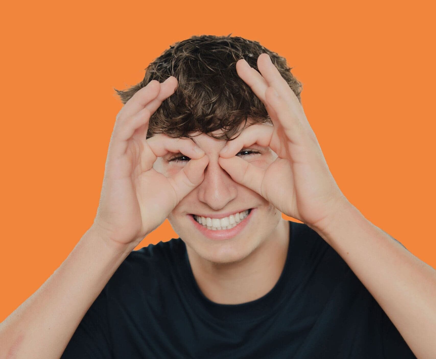 tooth-by-tooth-orthodontics-tooth-by-tooth-dr-patel-teen-making-binoculars-gesture-orange-background-big-smile