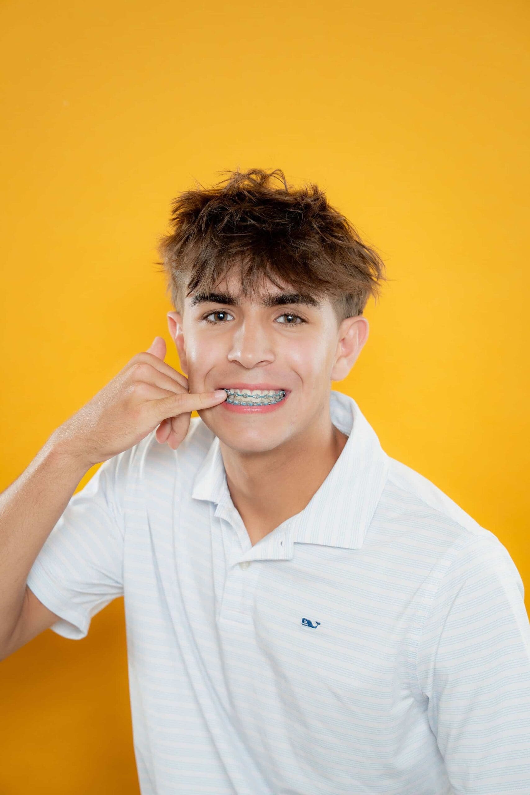 tooth-by-tooth-orthodontics-tooth-by-tooth-dr-patel-teen-pointing-metal-braces-smile-yellow-background