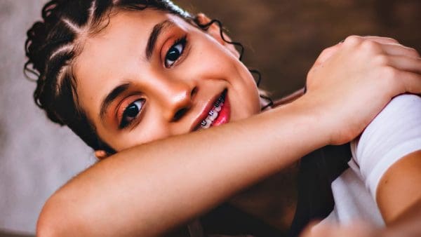 Smiling teen girl with braids showing her braces, the treatment that often fixes an underbite