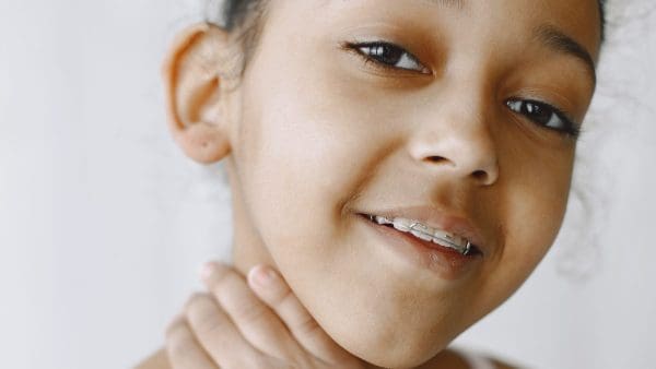 Smiling girl with braces resting her chin on her hand, at the age kids usually get braces